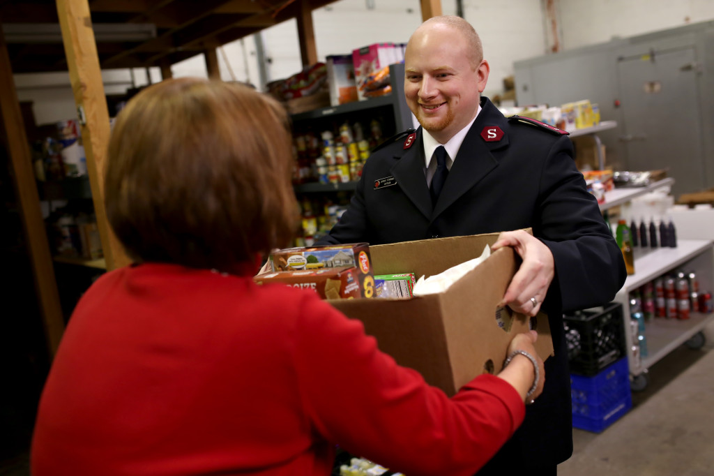 Volunteers organize boxes of food and Captain Joshua Stansbury gives the food to people in need.